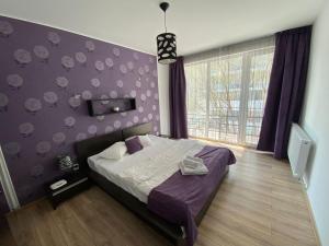 a bedroom with a bed and a purple wall at Apartament Ella T8 in Mamaia Sat/Năvodari