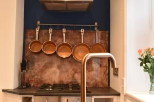 a bunch of copper pans hanging on a wall in a kitchen at The Cheltenham, stylish 1-bed Victorian apartment in Harrogate