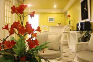 a living room with white chairs and red flowers at Hotel Galleria in Davao City