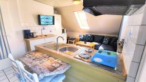 eine Küche mit einem Waschbecken und ein Wohnzimmer in der Unterkunft Gästehaus Zur alten Post - Wohnung Nord in Dornum