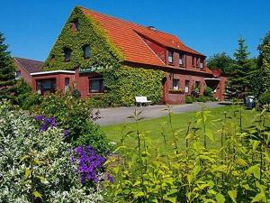 ein Haus mit rotem Dach und einem Garten mit Blumen in der Unterkunft Gästehaus Zur alten Post - Wohnung Nord in Dornum