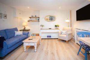 a living room with a blue couch and a table at STABLES Stylish comfortable peaceful cottage with parking and outdoor space in Holt