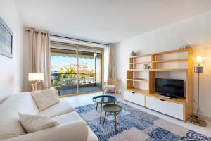 uma sala de estar com um sofá branco e uma televisão em Agence des Résidences - Appartements privés du 45 CROISETTE - Superieur em Cannes