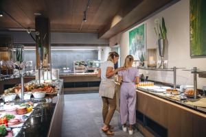 two women standing in a kitchen preparing food at Adler Resort in Saalbach-Hinterglemm