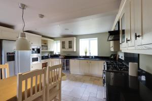 a kitchen with white cabinets and a stove top oven at Bretton House Farm Retreat in Chester