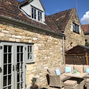 a stone building with a patio with a table and chairs at STABLES Stylish comfortable peaceful cottage with parking and outdoor space in Holt