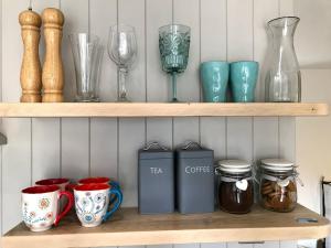 a shelf with cups and glass items on it at STABLES Stylish comfortable peaceful cottage with parking and outdoor space in Holt