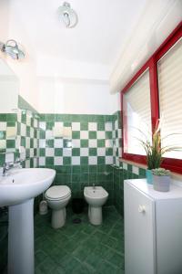 un bagno piastrellato verde con lavandino e servizi igienici di Estate4home - Villa Adriana a Piano di Sorrento
