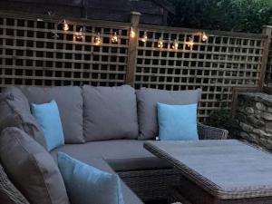 eine Couch auf einer Terrasse mit Tisch und Beleuchtung in der Unterkunft STABLES Stylish comfortable peaceful cottage with parking and outdoor space in Holt