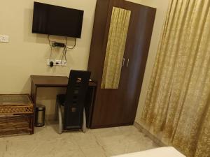 a room with a desk with a television and a door at Hotel cute orange in Chennai