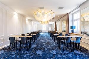 a row of tables and chairs in a room with a chandelier at Hotel Apis in Krakow