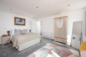 um quarto branco com uma cama e um espelho em Cynibre em Penzance