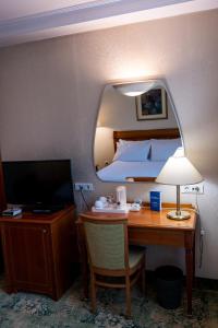 a hotel room with a desk with a bed and a television at Best Western Hotel Turist - Superior in Skopje
