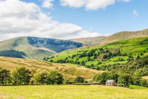 a green hillside with a barn in a field at Lake District cottage in 1 acre gardens off M6 in Penrith