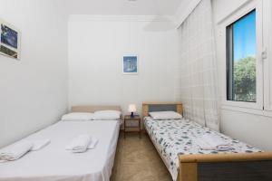 dwa łóżka w pokoju z oknem w obiekcie Aigli House w mieście Skala Kallirachis +32 zdjęcia
