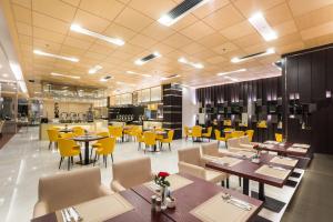 a restaurant with tables and chairs and yellow chairs at Best Western Plus Wanda Grand Hotel in Nonthaburi