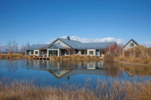 ein Haus auf einem See mit Spiegelung im Wasser in der Unterkunft Matuka Lodge in Twizel