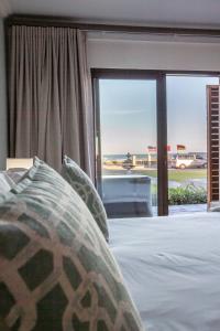 a bedroom with a bed and a large glass window at Chateau de Marine Boutique Hotel in Struisbaai