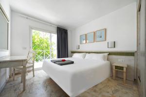 ein weißes Bett in einem Zimmer mit einem Schreibtisch und einem Fenster in der Unterkunft Vista Bonita - Gay and Lesbian Only Resort in Maspalomas