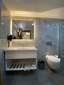 een badkamer met een wastafel, een toilet en een spiegel bij Gokcen Hotel & Apartments in Oludeniz