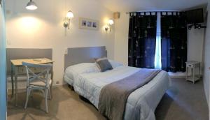 a bedroom with a bed and a table and a window at cit'hotel Hotel Las Cigalas in Villeneuve-lès-Béziers