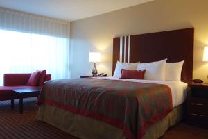 a hotel room with a large bed and a chair at Ramada by Wyndham Sacramento in Sacramento