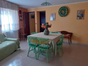 een tafel met groene stoelen en een vaas met bloemen erop bij Affittacamere GERANI in Capizzi