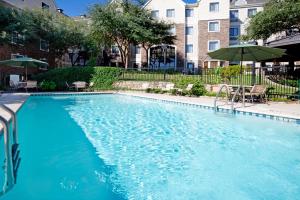 a large blue swimming pool with chairs and an umbrella at Sonesta ES Suites Austin The Domain Area in Austin