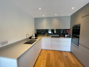 a kitchen with white cabinets and a wooden floor at Canalside Bude in Bude