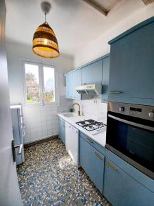 a kitchen with blue cabinets and a stove top oven at Villa les Pieds dans l'Eau in Trégastel