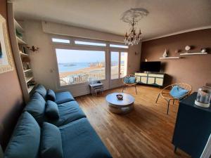 a living room with a blue couch and a large window at Villa les Pieds dans l'Eau in Trégastel