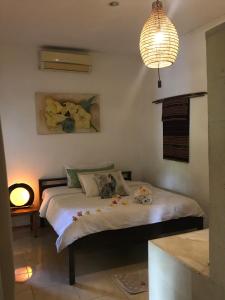 1 dormitorio con cama y lámpara de araña en Frangipani Garden Villa en Senggigi 