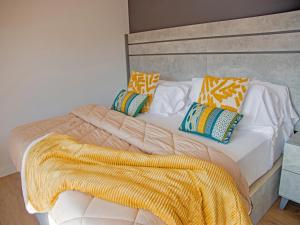 un letto con coperta gialla e cuscini sopra di Apartamentos Santander Maliaño Suites 3000 a Maliaño