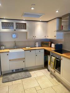 a kitchen with white cabinets and a sink at Reduced rates for this month! Beautiful cottage, 3 stories high with upstairs courtyard and set in an amazing location! The fantastic newly developed Town Mill with restaurants and craft shops on your doorstep Also only 2 minutes to the sea! , Sleeps 4 in Lyme Regis +15 photos
