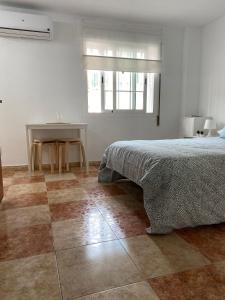 1 dormitorio con cama, mesa y ventana en Estudio Malagueño Centro 1ºB, en Málaga