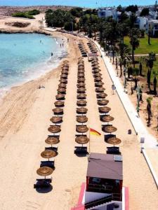 una playa con sombrillas y gente en la playa en Anmaria Beach Hotel & Spa, en Ayia Napa