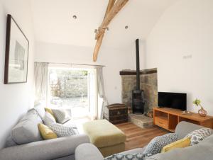 a living room with a couch and a fireplace at Bwthyn Gwenyn Yr Haf Summer Bee Barns in Nefyn