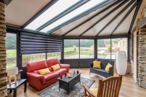 - un salon avec un canapé rouge et quelques fenêtres dans l'établissement LA LONGERE DU TERTRE - Charmante longère de 400m2 proche plage, à Cancale