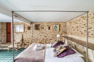 - une chambre avec un lit à baldaquin dans un mur en briques dans l'établissement LA LONGERE DU TERTRE - Charmante longère de 400m2 proche plage, à Cancale