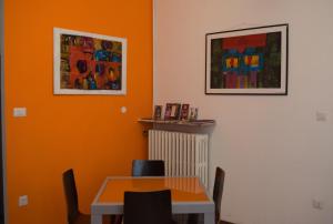 un comedor con una pared de color naranja y una mesa en Il Borgo appartamento Clelia, en Parma
