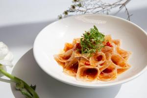 a white plate of pasta with greens on top at InterContinental Hefei, an IHG Hotel in Hefei