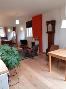 a living room with a table and a grandfather clock at D'R Pletsch in Berg en Terblijt