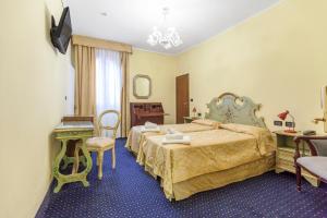 a hotel room with two beds and a table and a chair at Hotel Malibran in Venice
