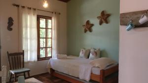 1 dormitorio con cama, ventana y silla en Chalé Juliet, en Pirenópolis