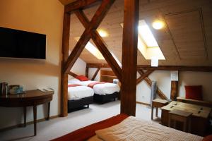 a room with two beds and a desk and a tv at Gruyère Rooms in Gruyères