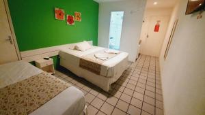 um quarto com duas camas e uma parede verde em Pousada Pedras do Porto em Porto de Galinhas