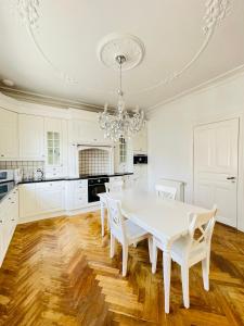 a white kitchen with a white table and chairs at aday - Aalborg City Center big apartment in Aalborg