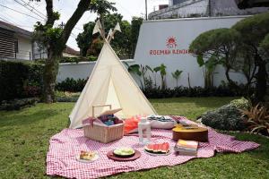 een picknicktafel met eten en een tipi bij Roemah Renjana Bandung in Bandung