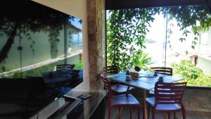 einen Tisch und Stühle auf einer Terrasse mit einem großen Fenster in der Unterkunft Flat com portão na Praia in Angra dos Reis