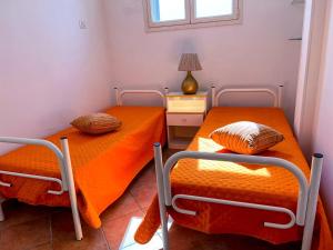 マリーナ・ディ・マンカヴェルサにあるCasa Vacanza MANCAVERSAのオレンジのシーツが備わる客室内のベッド2台